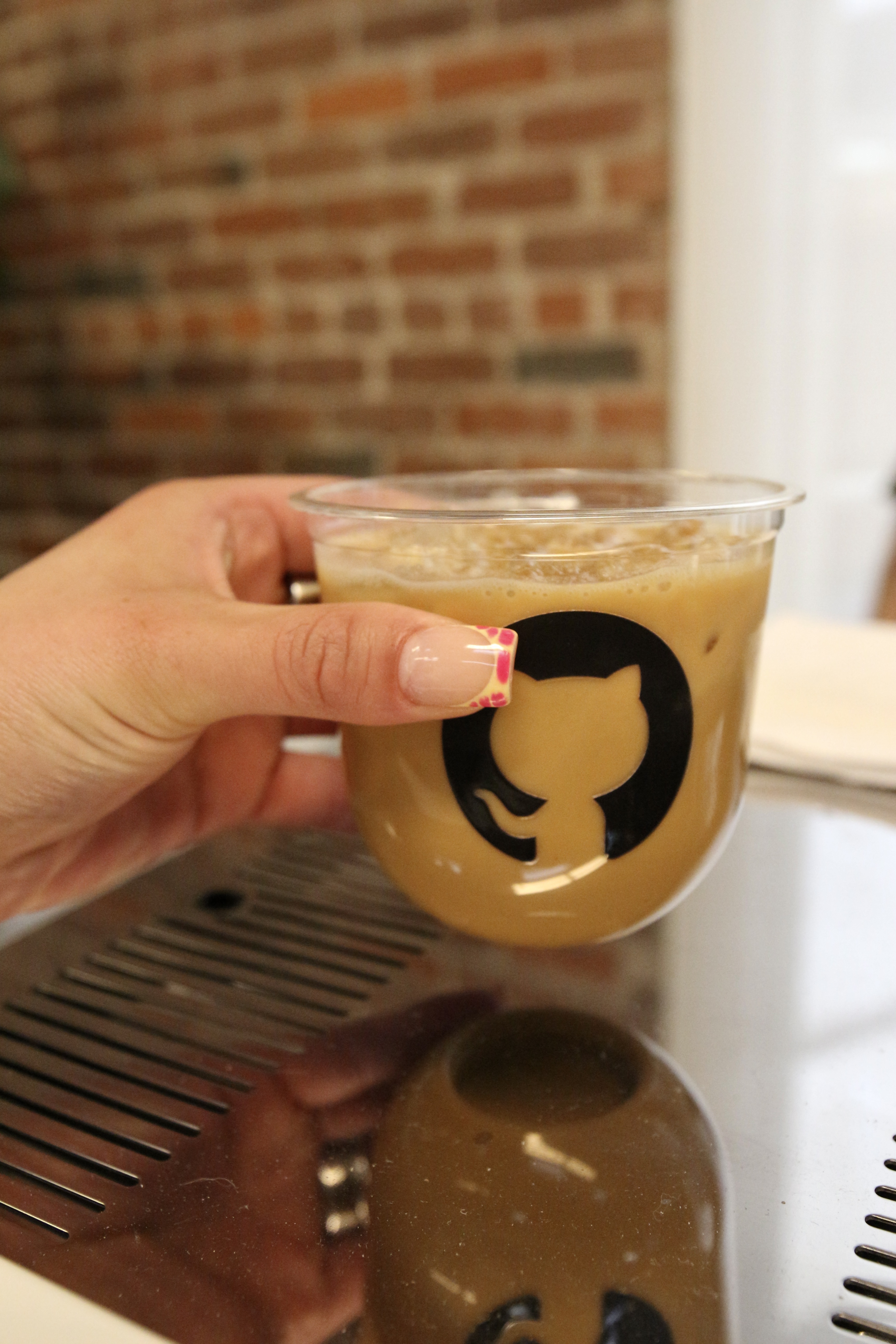 Iced latte in a GitHub-branded clear cup held at the Fez Coffee activation event.