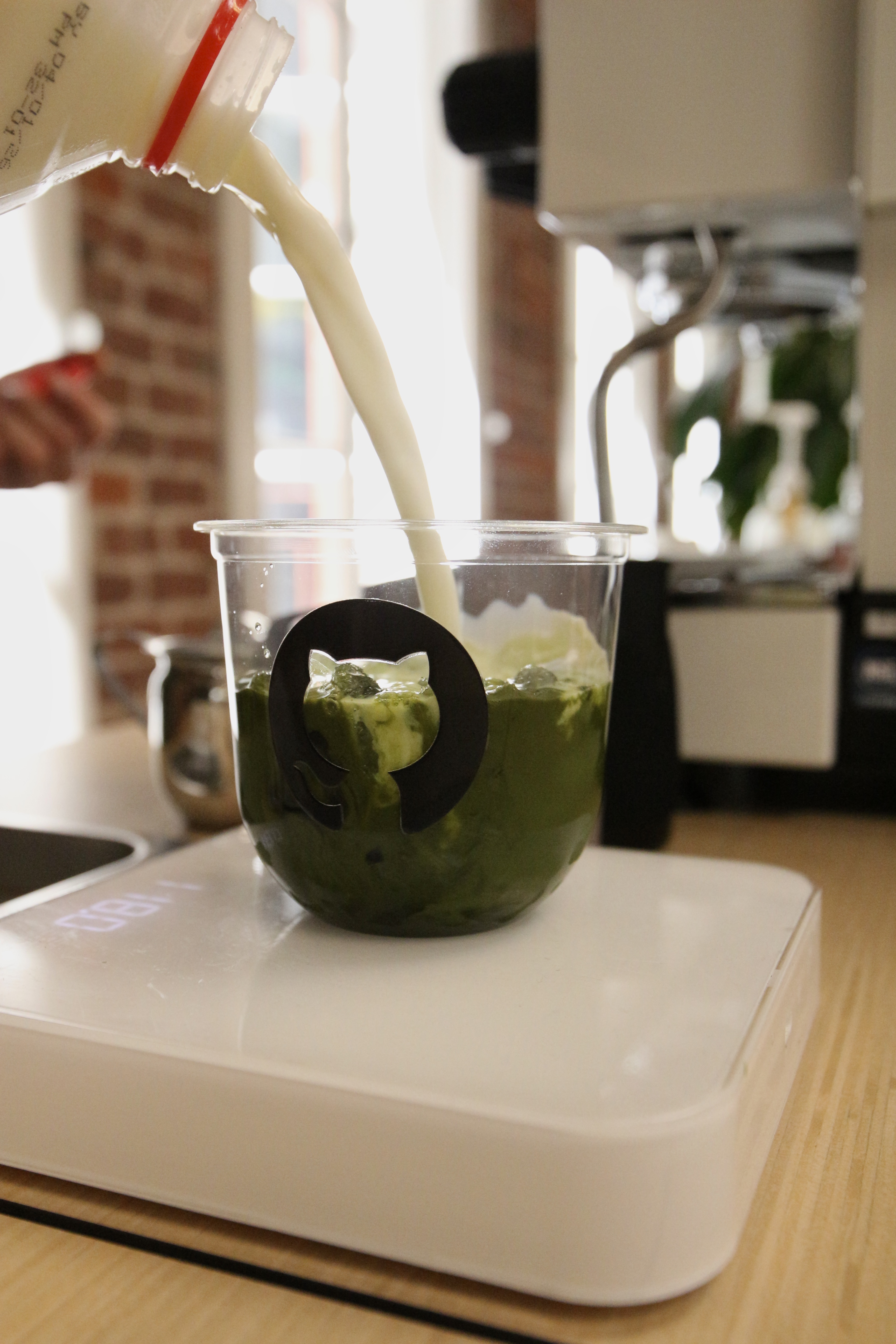 Iced ceremonial matcha being poured into a GitHub-branded cup at the Fez Coffee activation.