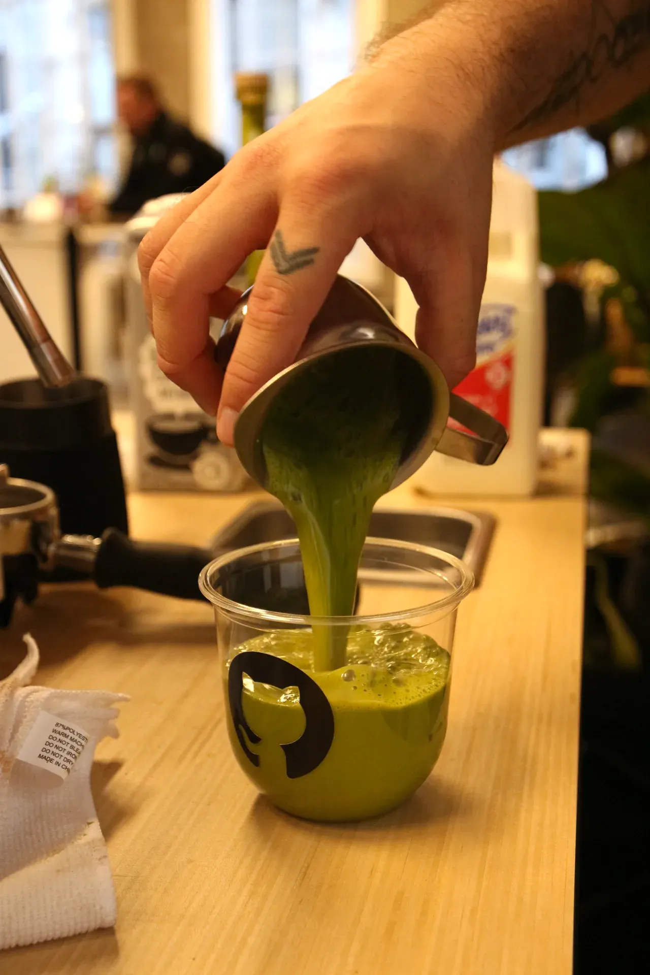 Barista pouring ceremonial matcha into a GitHub-branded branded cup at the Fez Coffee espresso bar.