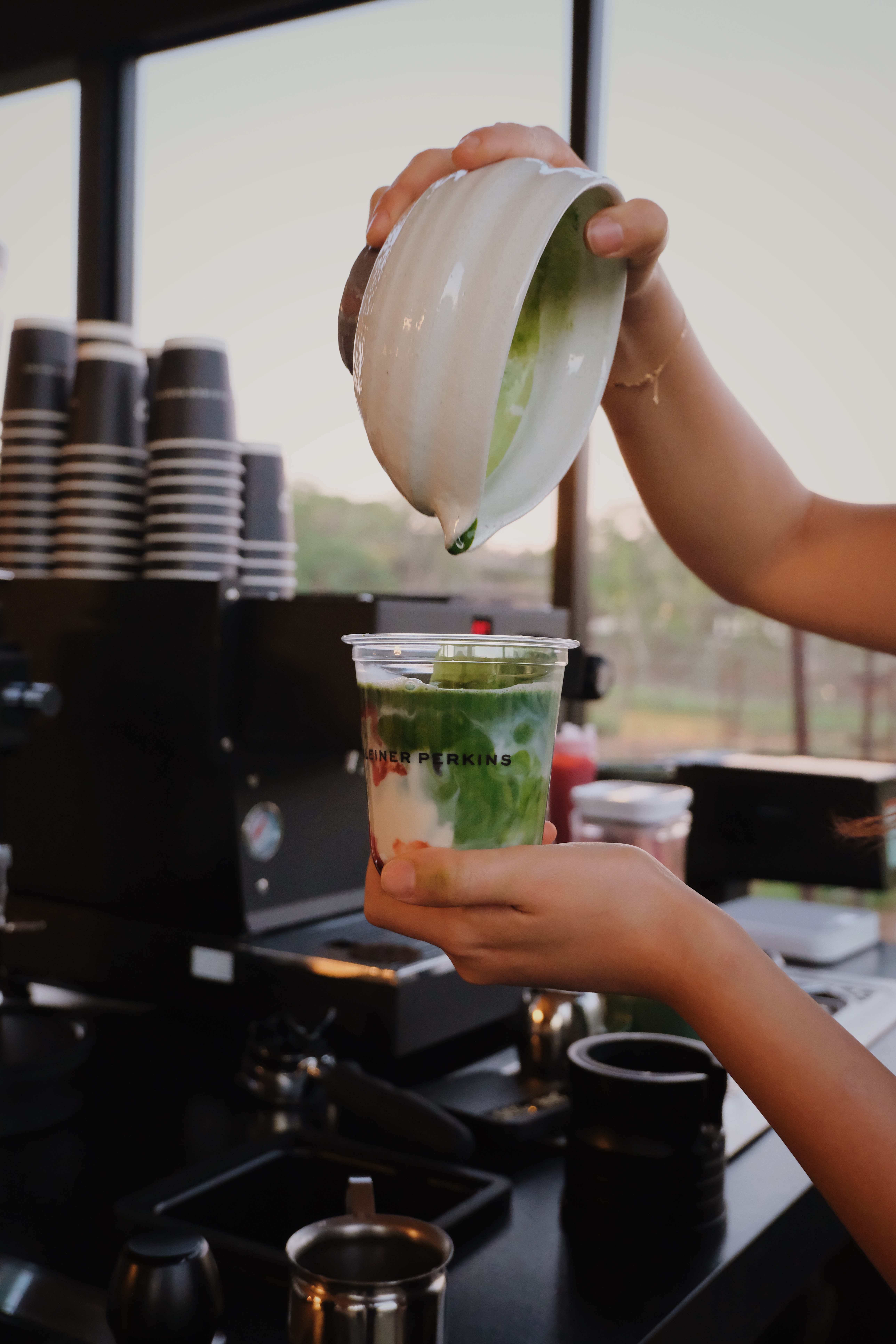 Barista pouring ceremonial matcha into a custom branded cup at the Fez Coffee espresso bar.